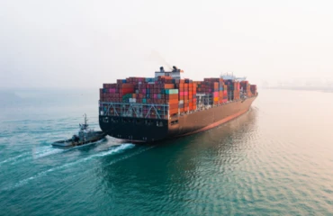 A large cargo ship is guided by a tug boat